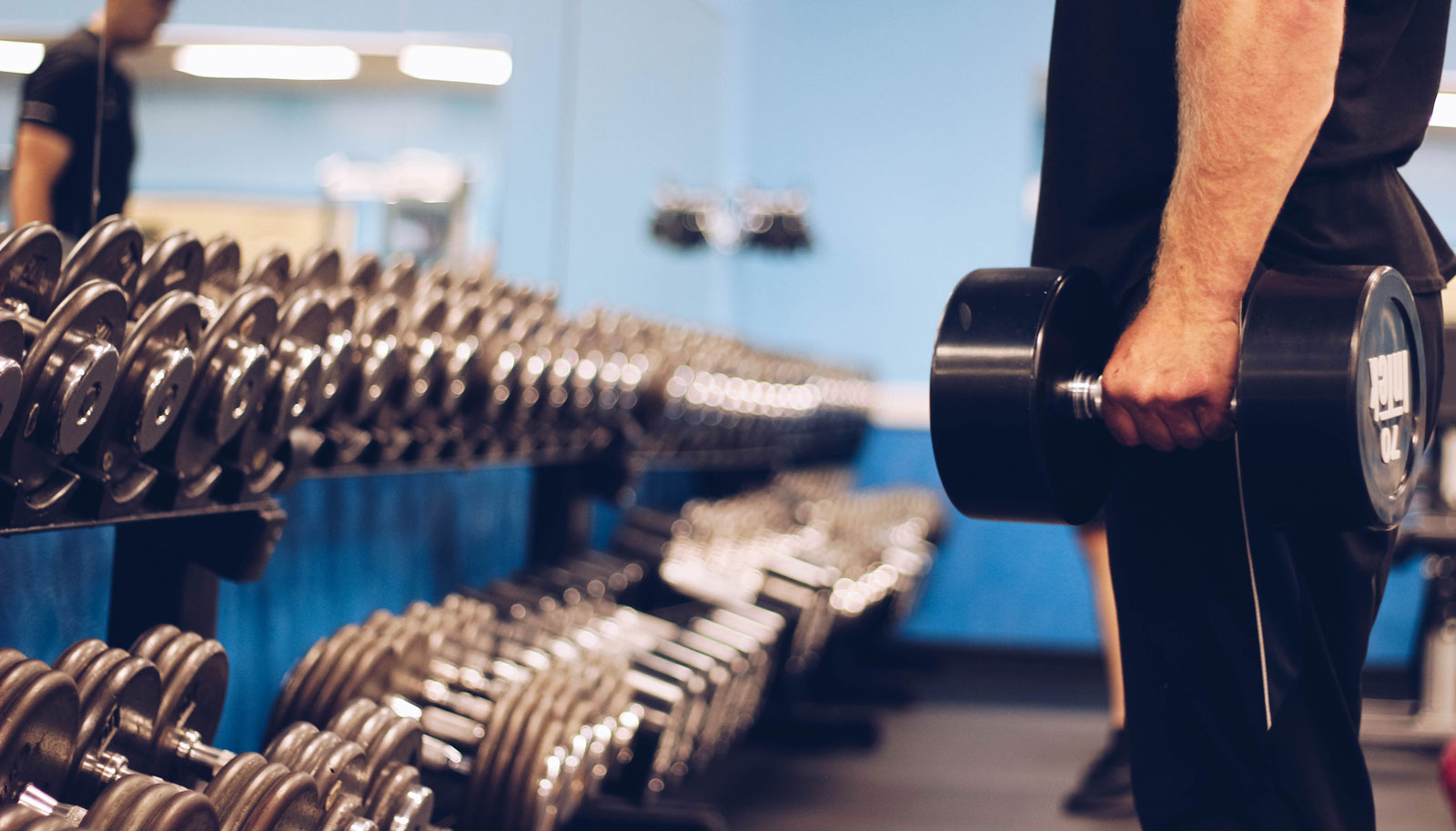 Man holding dumbbells in front of the mirror in the weight room at Parkside Fitness