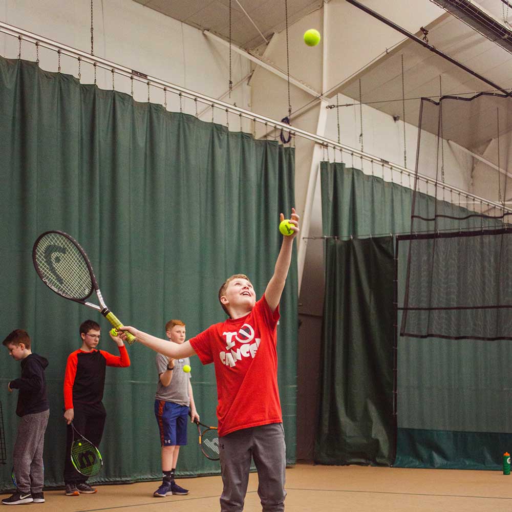 Little boy practicing his tennis serve
