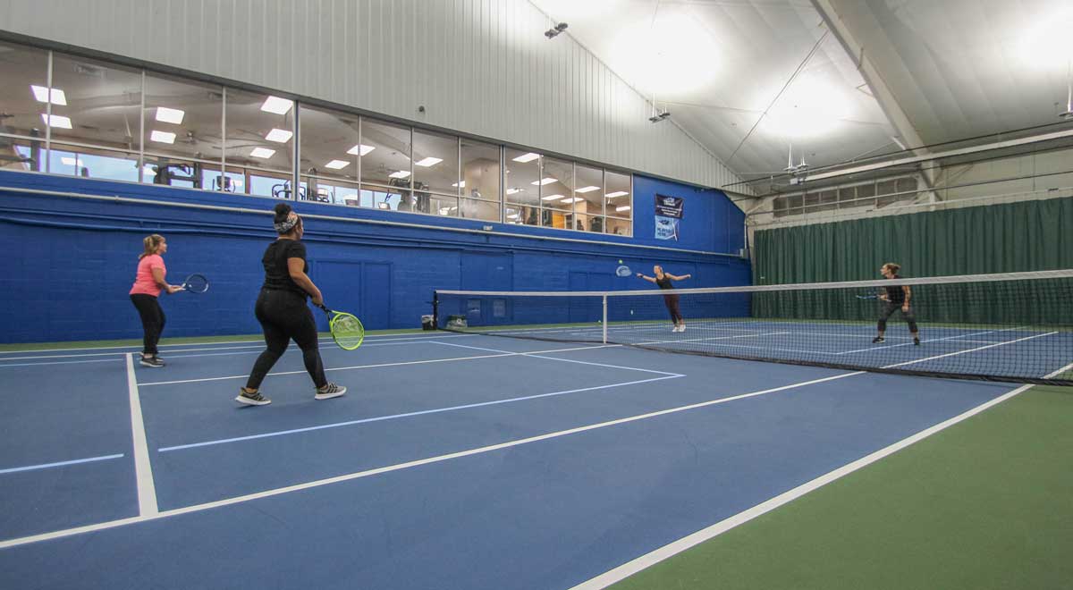 Women playing tennis on a Parkside Fitness indoor tennis court