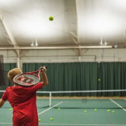 Boy learning to serve a tennis ball