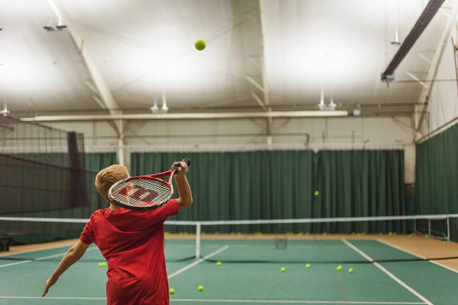 Boy learning to serve a tennis ball